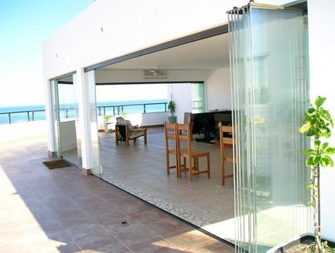 Cortina de vidro aberta em varanda gourmet com vista mar